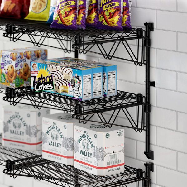 A Regency black wire shelf with food and snacks on it.