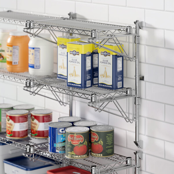 A Regency stainless steel wall-mount shelf with cans of food on it.