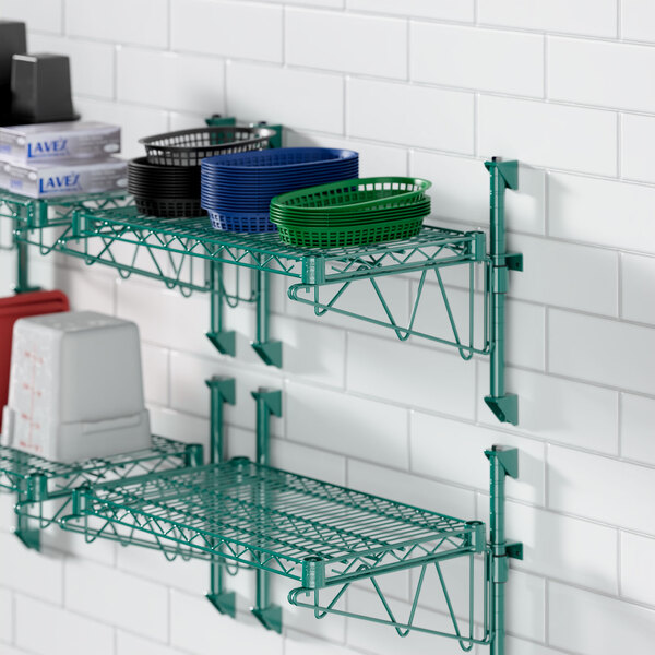 A green Regency wire wall-mount shelf with dishes and pots on it.