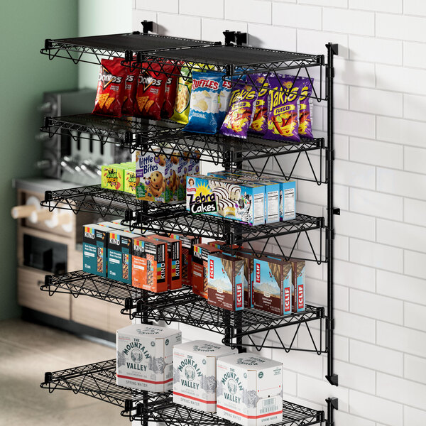 A Regency black wire wall-mount shelf with snacks on it.