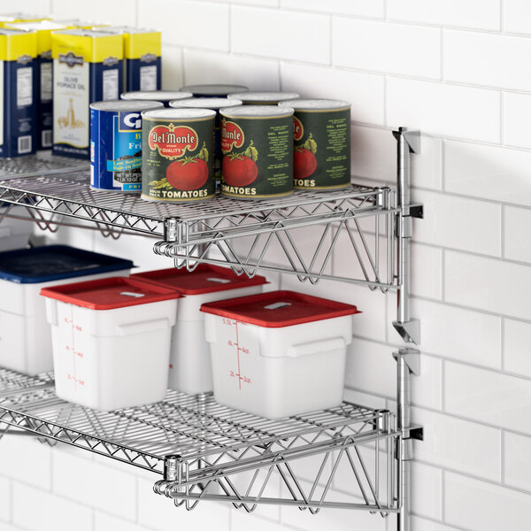 A metal Regency wall-mount shelf with white containers and cans on it.