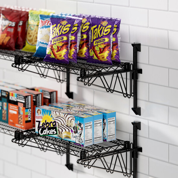 A Regency black wire shelf with snacks and boxes on it.