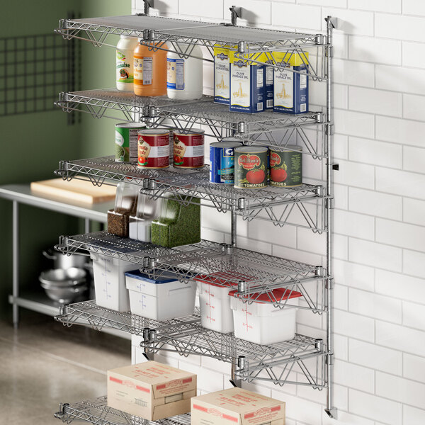 A Regency chrome wall-mount shelf post in a professional kitchen with shelves filled with food.