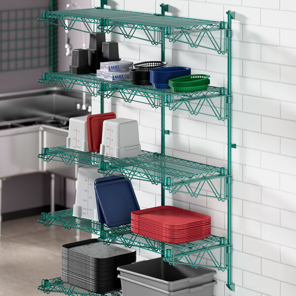 A Regency green wire wall shelf with dishes and containers on it.