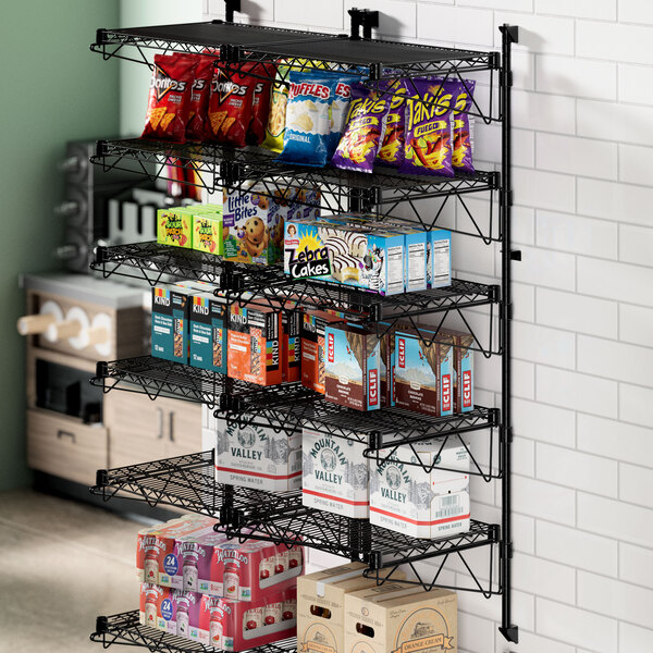A Regency black metal wall-mount shelf post with snacks and drinks on it.