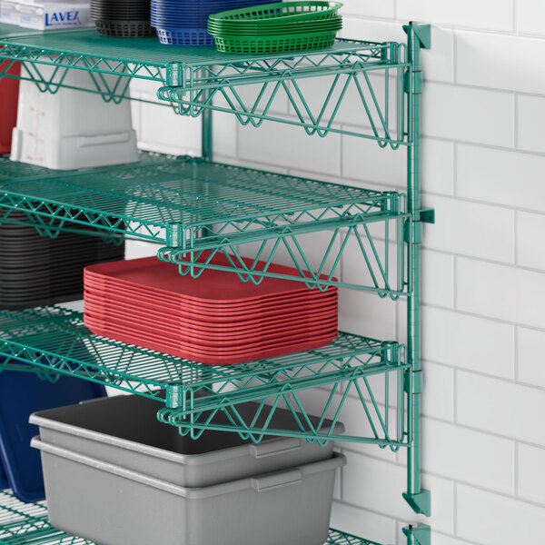 A green metal Regency wall-mount shelf with dishes and plastic containers.