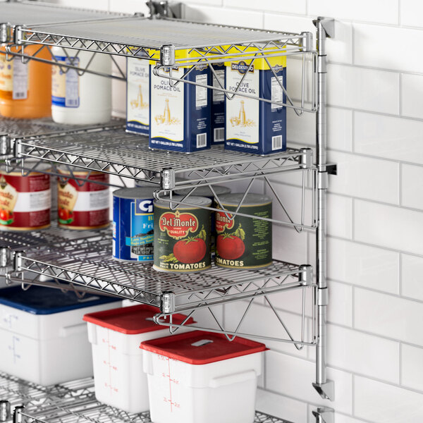 A professional kitchen with Regency stainless steel wall-mount shelves holding food items.