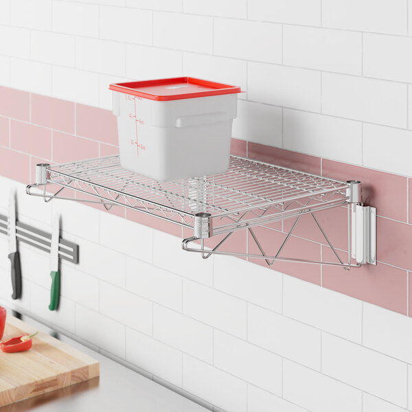 A Regency stainless steel wall-mount wire shelf with a white and red container on it.
