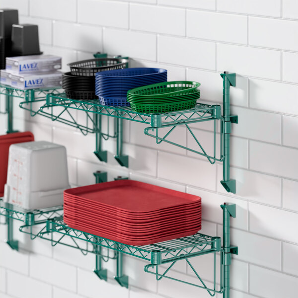 A Regency green wire shelf with dishes, plates, and bowls on it.