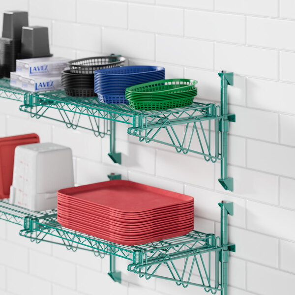 A green Regency wall-mounted wire shelf with dishes and plates on it.