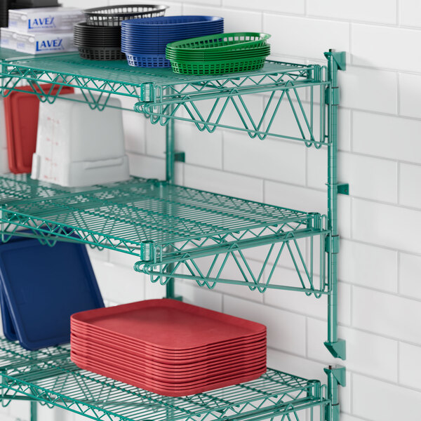 A Regency green metal wall-mount shelf with white containers and plastic plates.