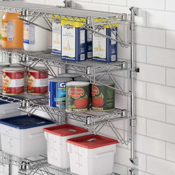 A Regency chrome wall-mount shelf post with double brackets holding a shelf with food containers and cans.