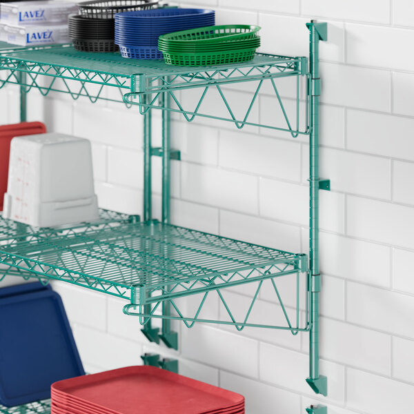 A green metal Regency wire shelf with dishes and plastic containers on it.