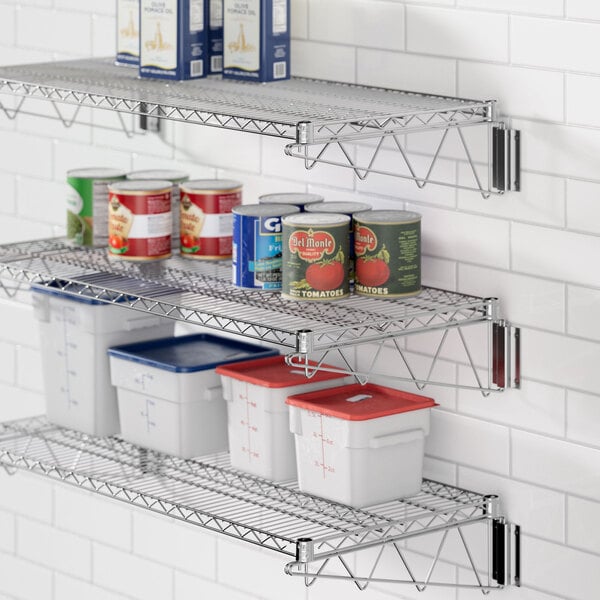 A chrome Regency wall-mount wire shelf with food containers and cans on it.