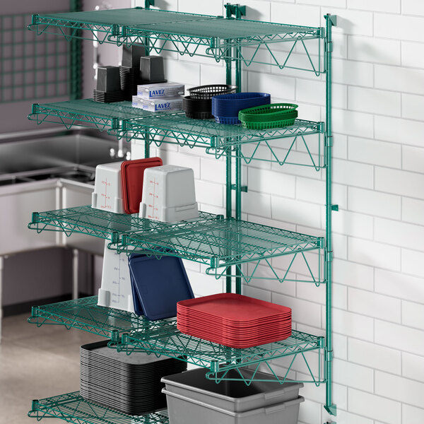 A green metal Regency wall-mount wire shelf with blue trays on it.