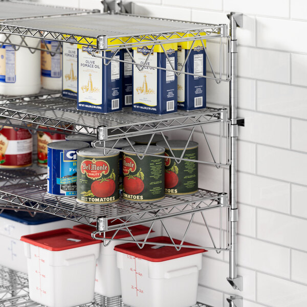 A metal Regency wall-mount shelf with food cans and containers on it.