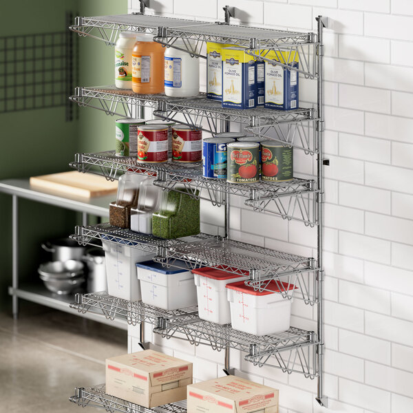 A Regency stainless steel wall-mount shelf post with double brackets holding shelves in a kitchen.