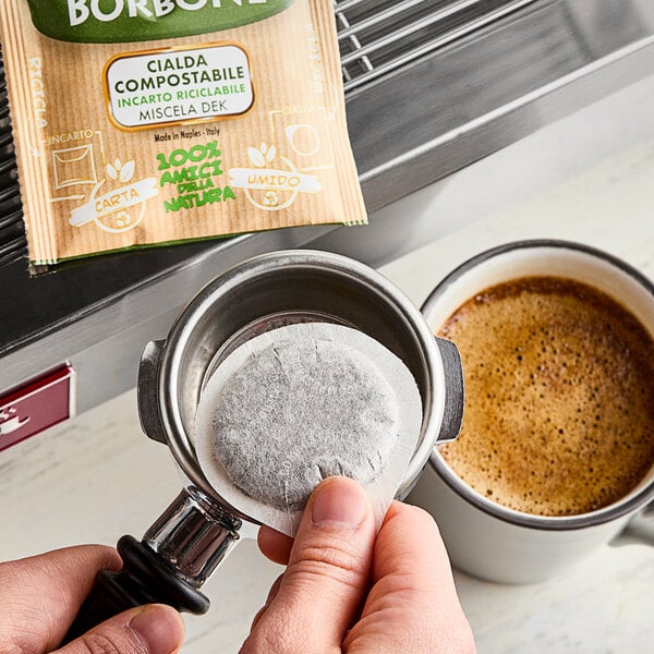 A person using a Caffe Borbone decaf espresso pod to make coffee.