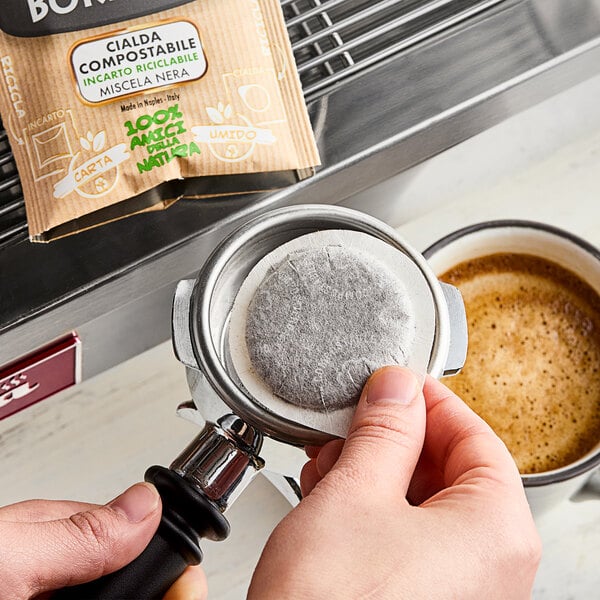 A person using a Caffe Borbone espresso pod in a coffee filter.