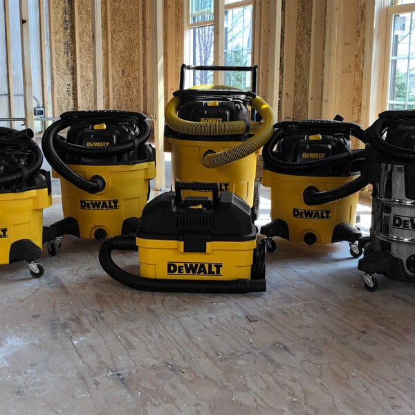 A yellow and black DeWalt wet/dry vacuum with a tool kit and accessory storage bag.
