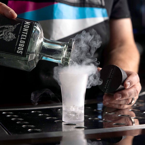 A man pouring liquid into a Flavour Blaster JetChill plastic shot glass with smoke coming out of it.