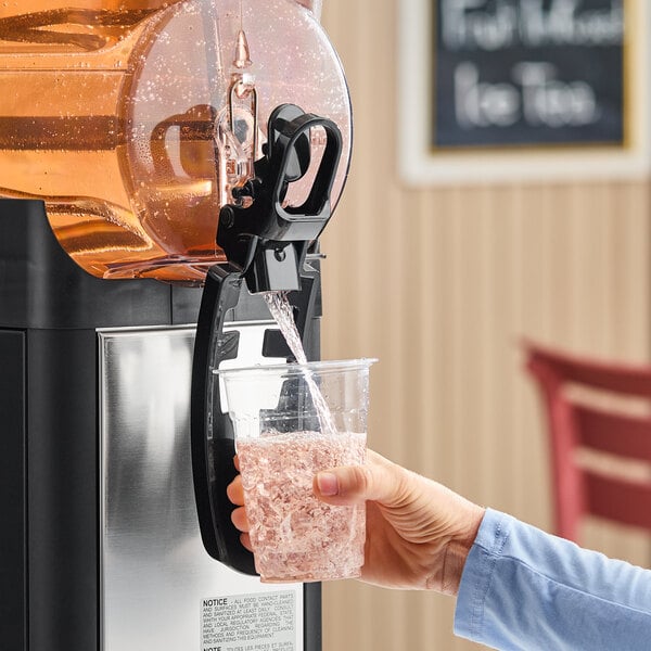 A person dispensing a pink beverage from a Narvon single 3-gallon refrigerated beverage dispenser into a clear plastic cup.