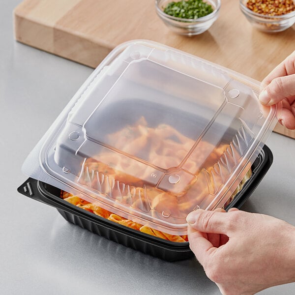 A person holding an Ecopax plastic container with food inside and placing a plastic lid over it.