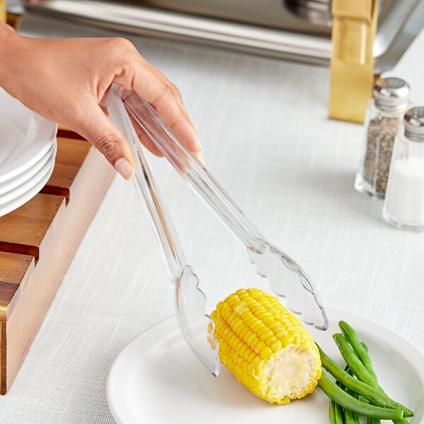 Clear polycarbonate scallop grip tongs serving corn on the cob at a salad bar.