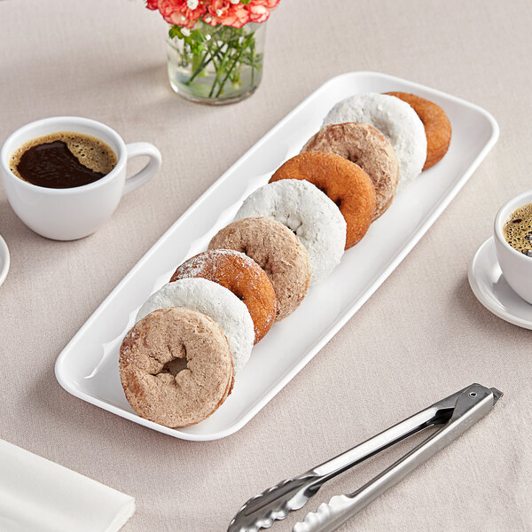 A white Sabert Mozaik plastic platter of donuts on a table with coffee cups.