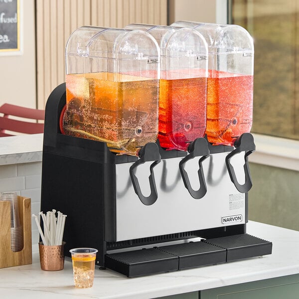 A triple 5-gallon bowl refrigerated beverage dispenser with three clear containers and black dispensing handles, designed for serving cold drinks.
