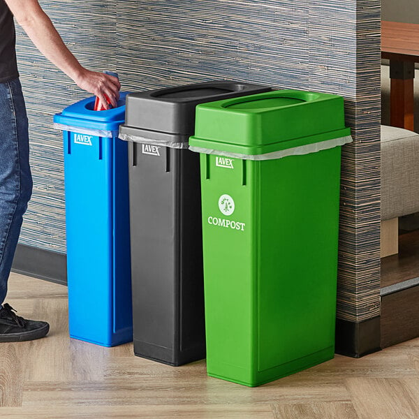 A man standing next to a Lavex 3-stream rectangular trash station with green, black, and blue lids.