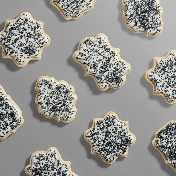 A collection of sugar cookies decorated with white icing and coarse black sanding sugar.