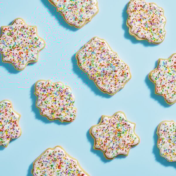 A cookie with white frosting and colorful Adourne rainbow sparkling sugar sprinkles.