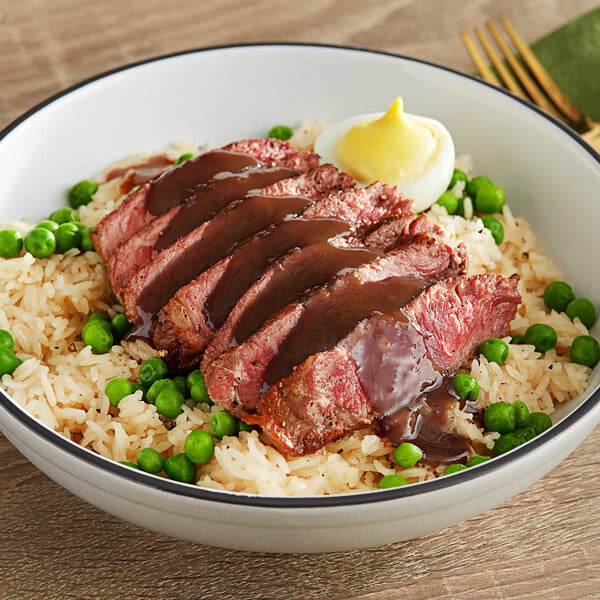 A bowl of rice with meat and peas topped with Pickapeppa Original Sauce.