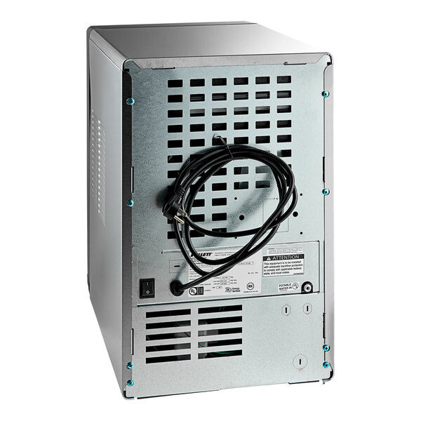 A silver rectangular Follett ice maker with a black wire.