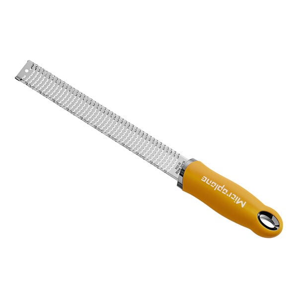 A yellow and silver Microplane zester grater with a handle.