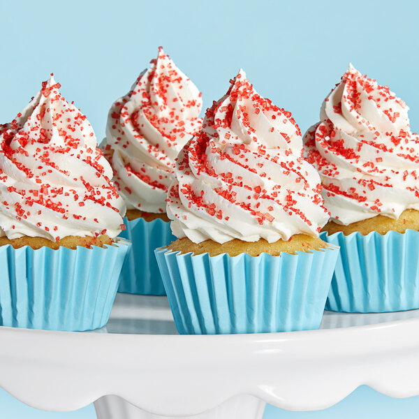 A cupcake with white frosting and red Adourne sparkling sugar.