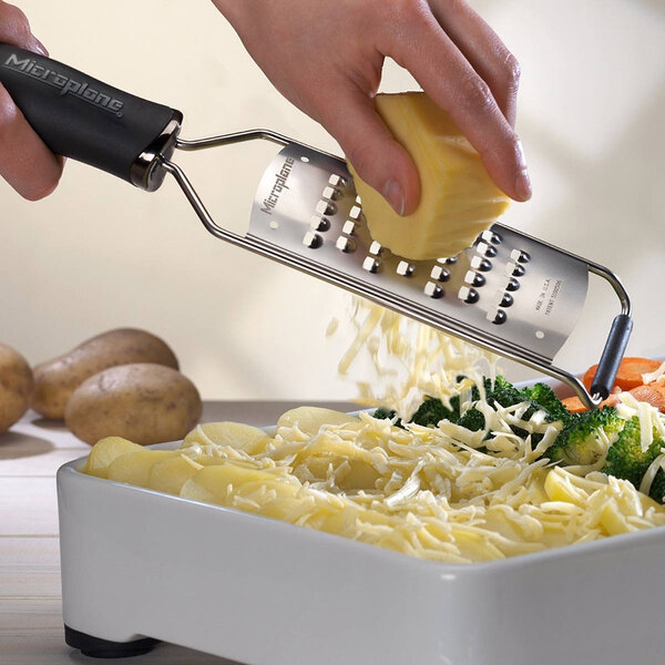 A person grating cheese on a Microplane extra-coarse grater.