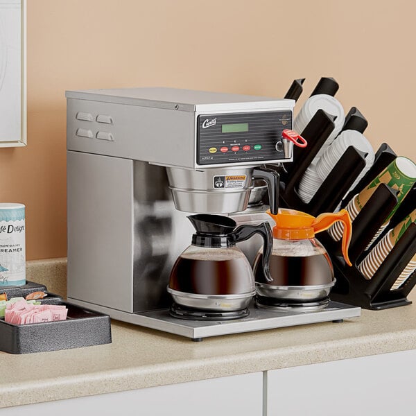 A Curtis commercial coffee maker on a counter with a coffee pot.