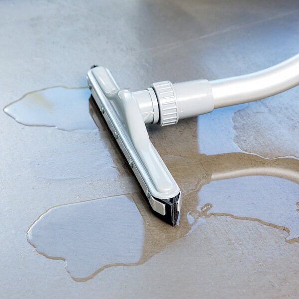 A ProTeam wet and dry vacuum cleaner with white attachments on a tile floor.