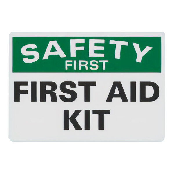 A white sign with green and black letters that says "Safety First / First Aid Kit"