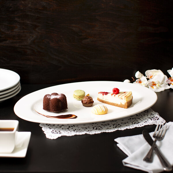 A 10 Strawberry Street white oval porcelain platter with a piece of cheesecake with raspberries on top.