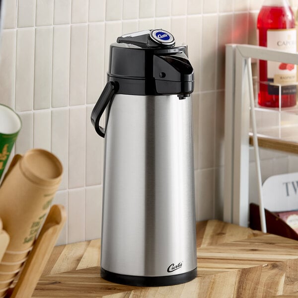 A stainless steel airpot with a black lever lid and handle, designed for beverage dispensing.