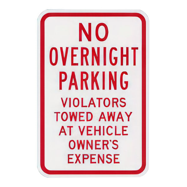 A white Lavex aluminum parking lot sign with red text and a red border that says "No Overnight Parking / Violators Towed Away At Vehicle Owner's Expense"