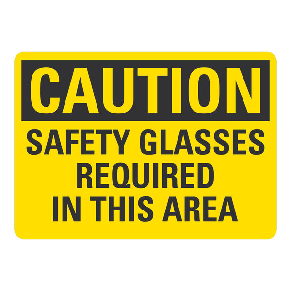 A yellow and black aluminum sign that says "Caution Safety Glasses Required In This Area"