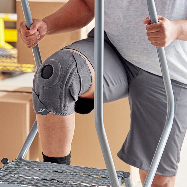 A man wearing a 3M Futuro knee stabilizer over his pants.