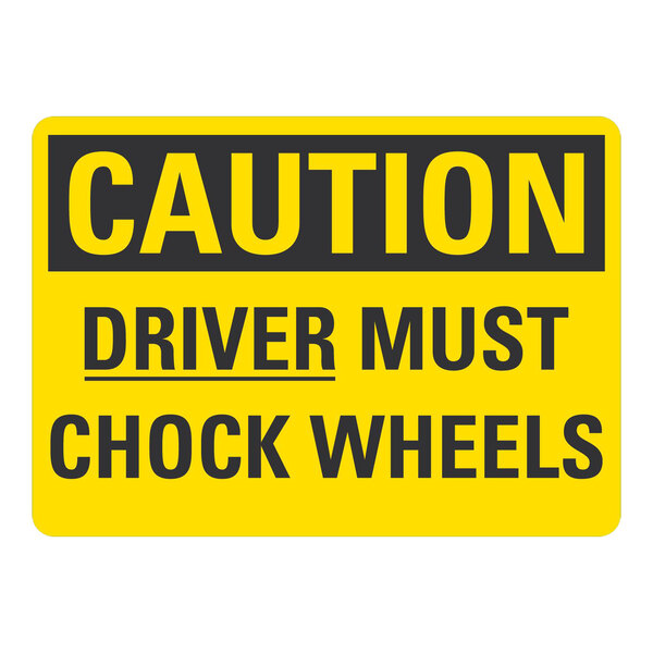 A yellow rectangular aluminum sign with black text that says "Caution / Driver Must Chock Wheels"