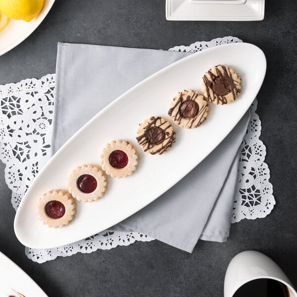 A white 10 Strawberry Street oval porcelain leaf platter holding cookies on a table.