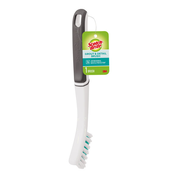 A 3M Scotch-Brite grout and detail brush with a green and white handle.