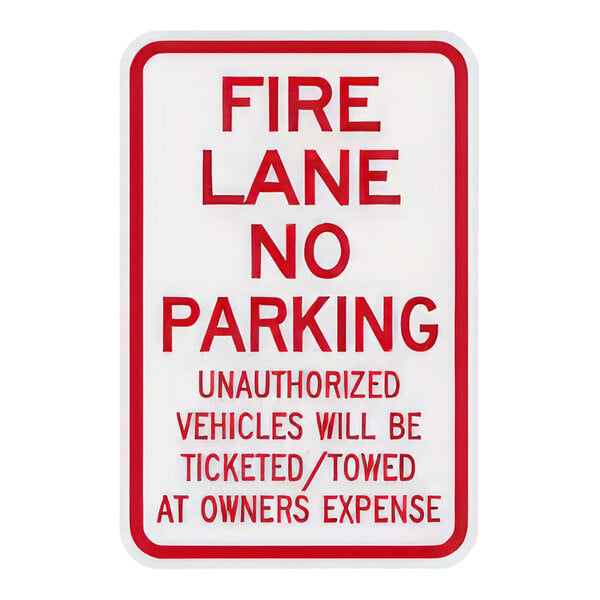 A white rectangular aluminum sign with red text and a red border that says "Fire Lane - No Parking - Unauthorized Vehicles Will Be Ticketed - Towed At Owner's Expense"